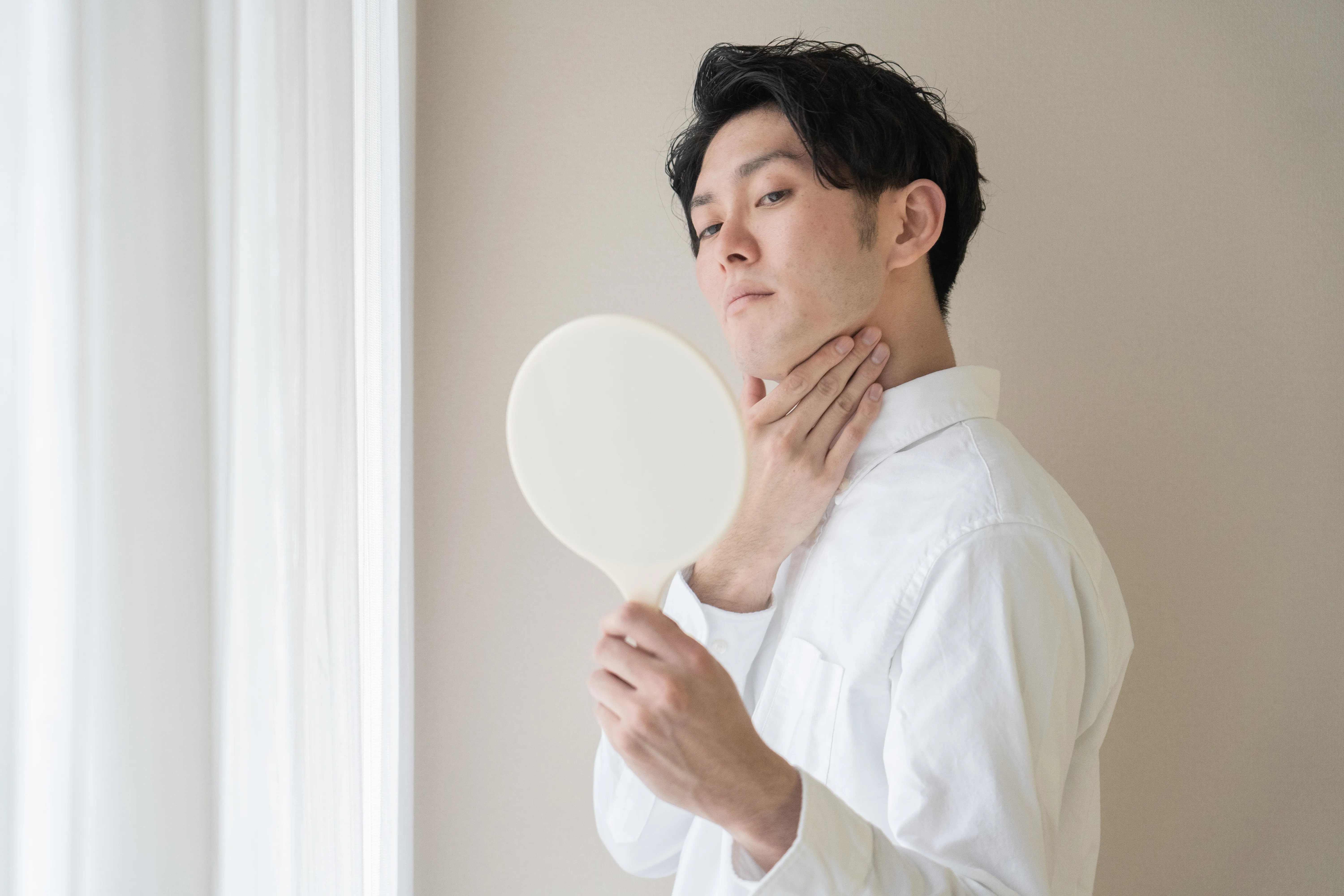 手鏡で肌を確認する男性